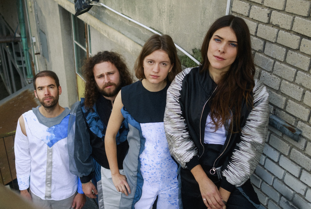 die vier Musiker:innen von BARANY stehen hintereinander auf der Treppe und schauen hoch in die Kamera