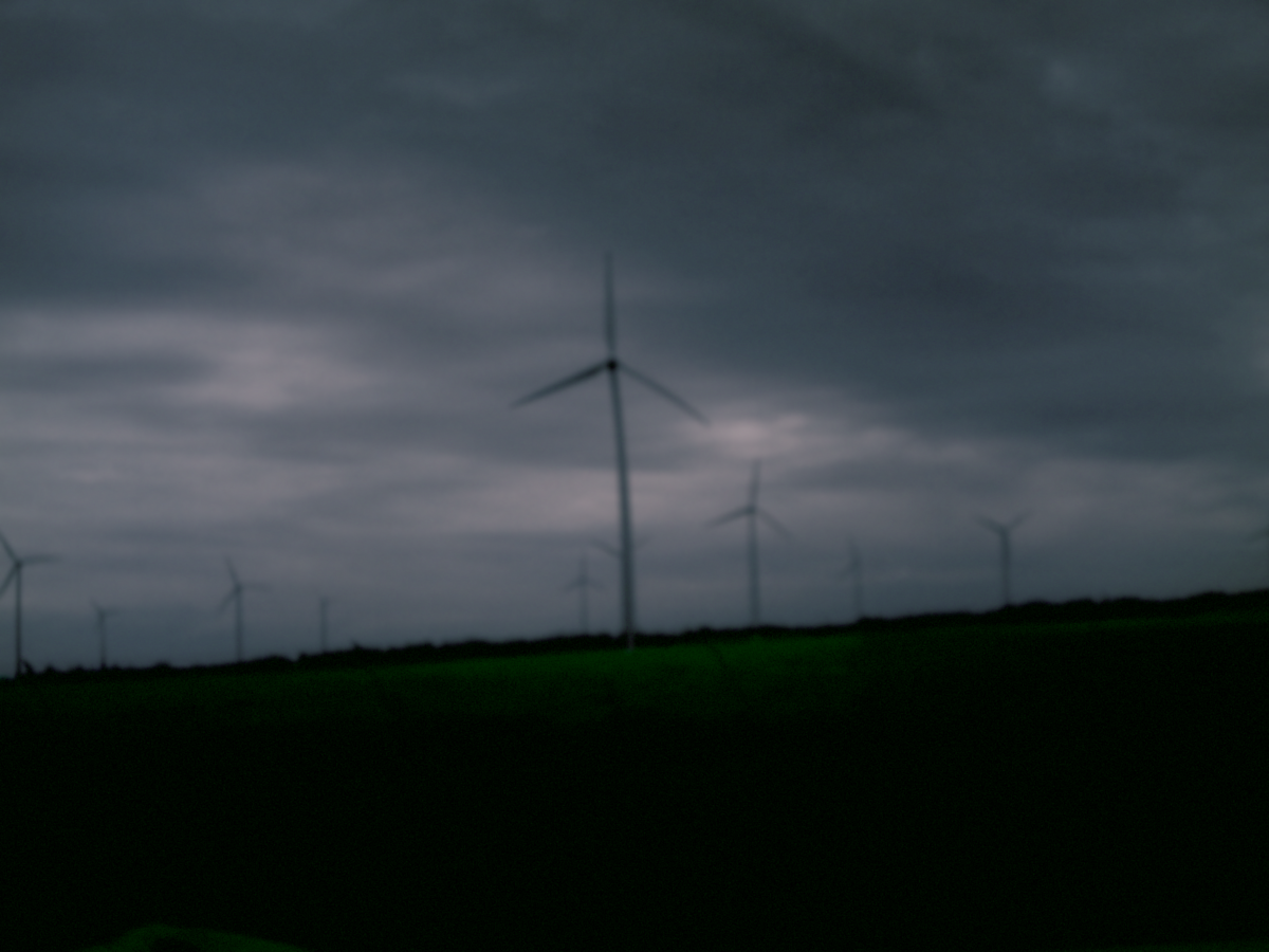 Windräder kurz vor Einbruch der Nacht unter dunklen leicht violetten Wolken