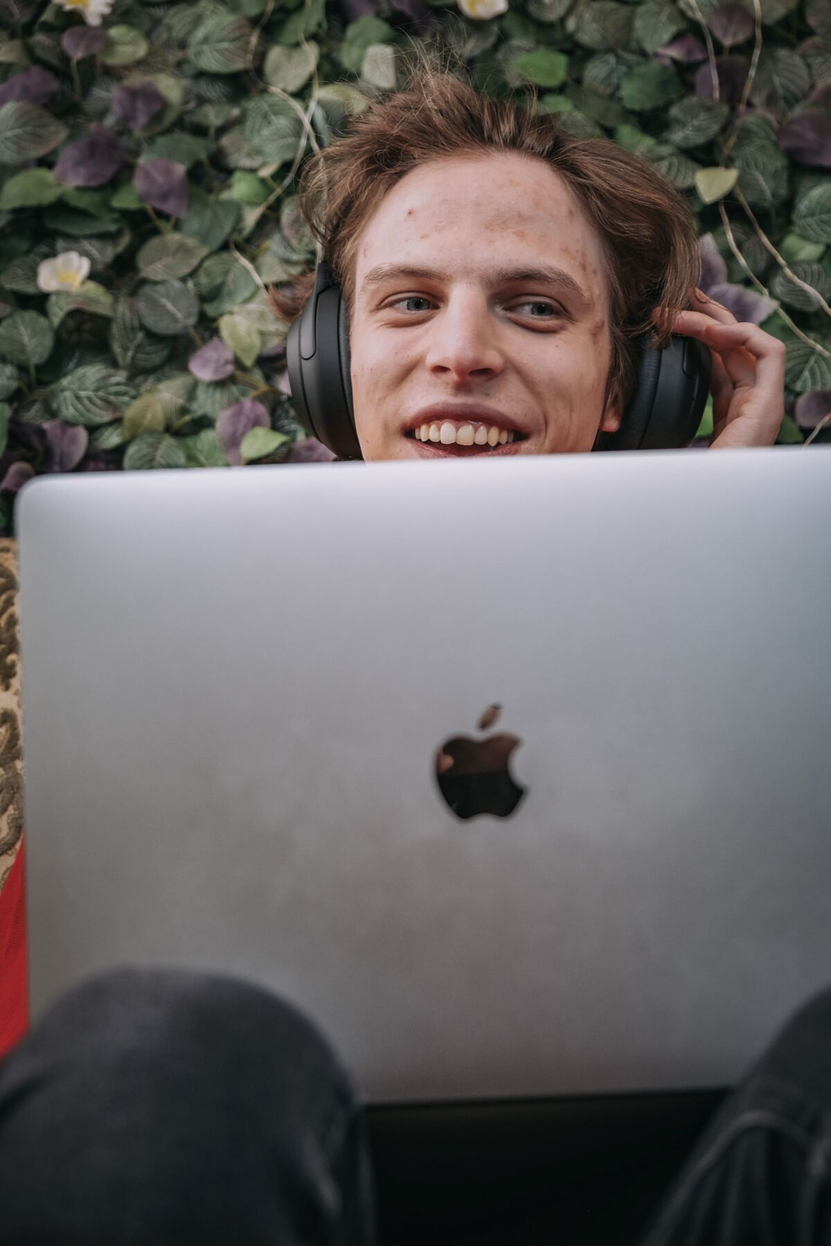 Vili Polajnar, der mit Kopfhörern hinter einem Laptop sitzt, die er gerade abzieht und offen lacht