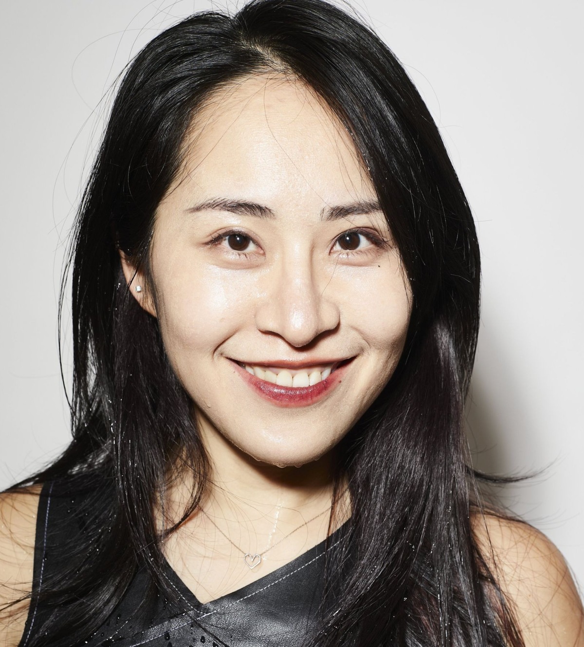 Porträt von Yi-Zhen Tsai, die in einem schwarzen Kleid vor einem weissen Hintergrund sympathisch in die Kamera lacht.