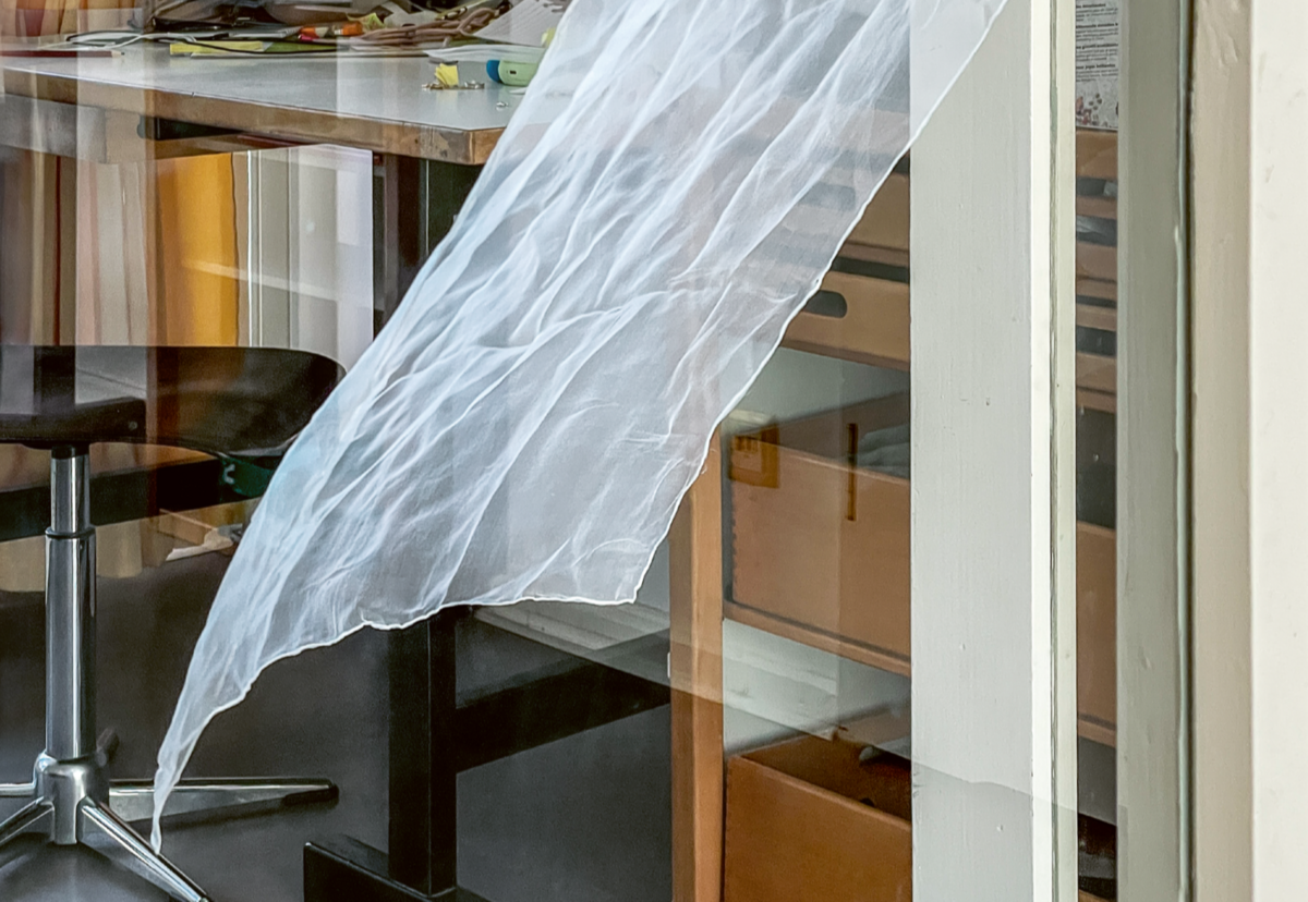 vom Wind bewegtes Stoffstück vor Schreibtisch