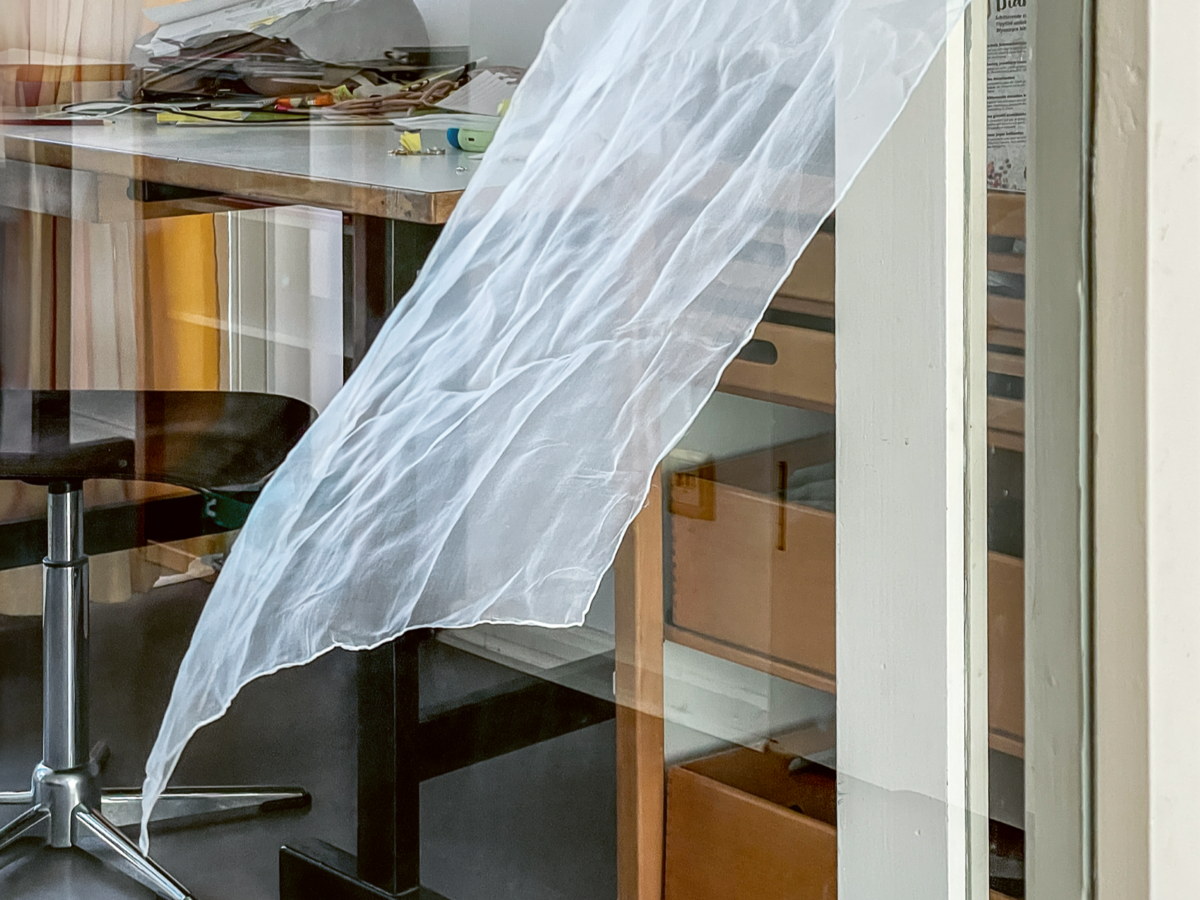 vom Wind bewegtes Stoffstück vor Schreibtisch