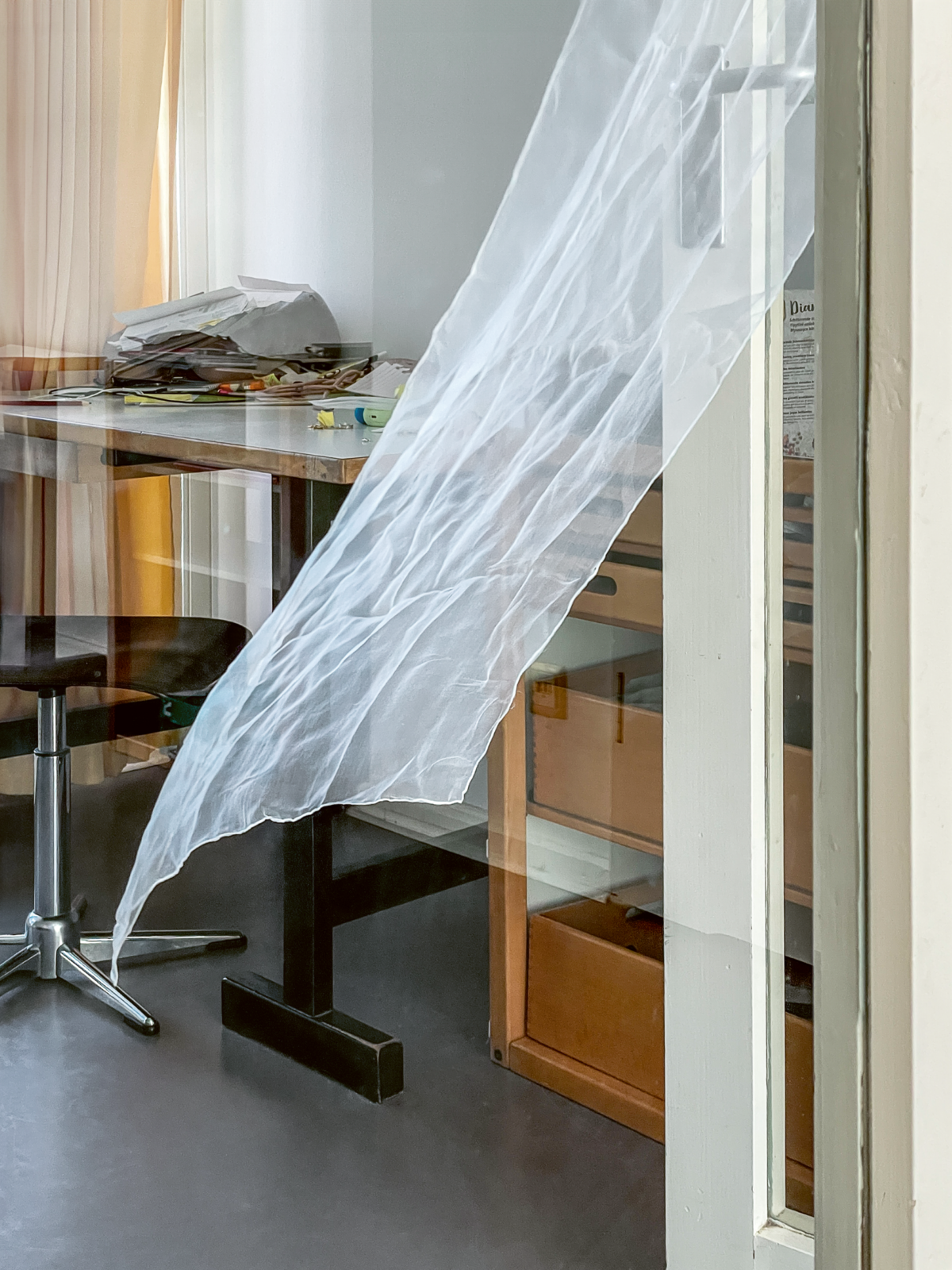 vom Wind bewegtes Stoffstück vor Schreibtisch