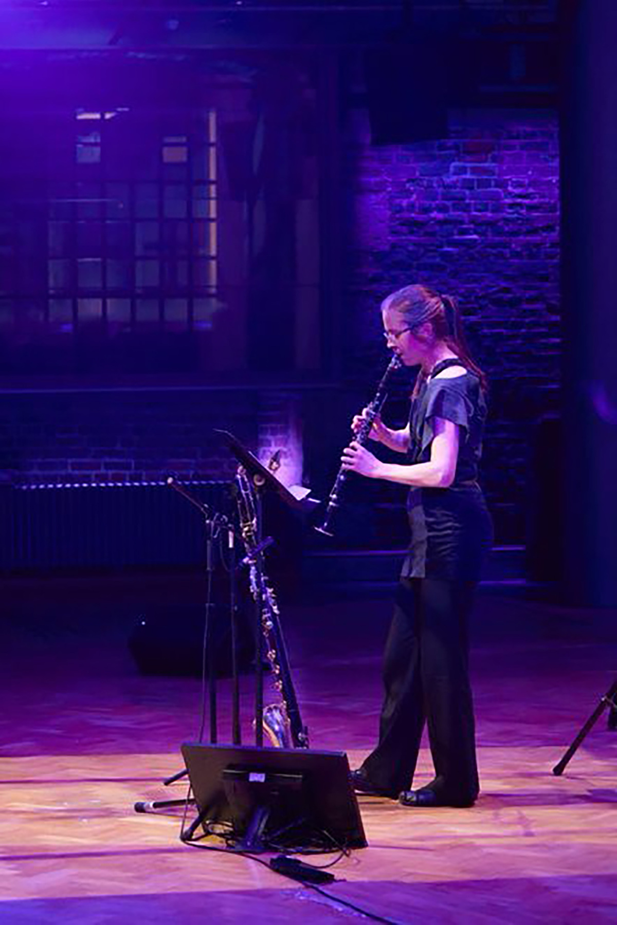 Heather Roche, die auf einer Bühne Klarinette spielt in violettem Licht