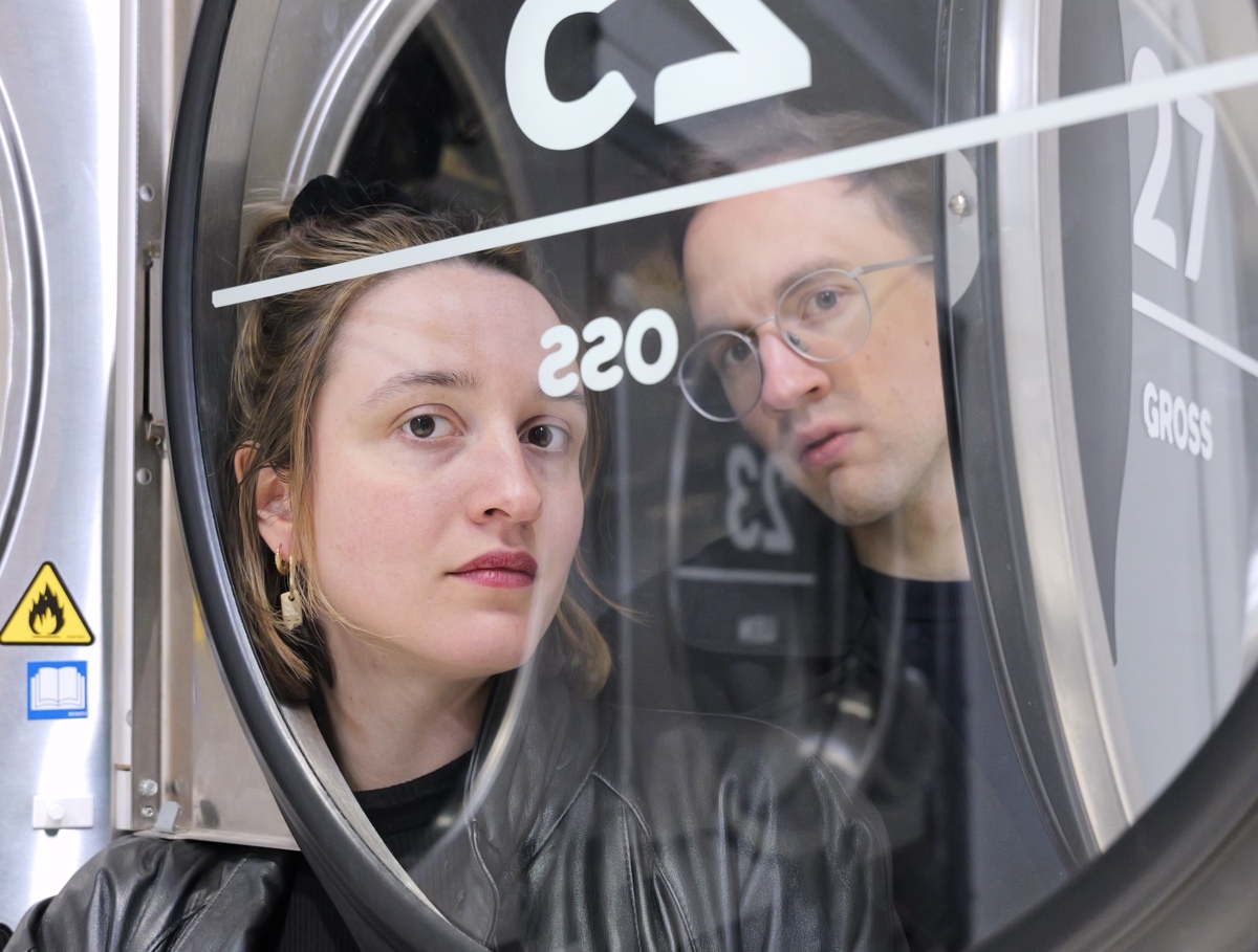 Foto von Ludmilla Mercier und Jakob Böttcher, die leicht verwirrt durch eine Waschtrommel schauen