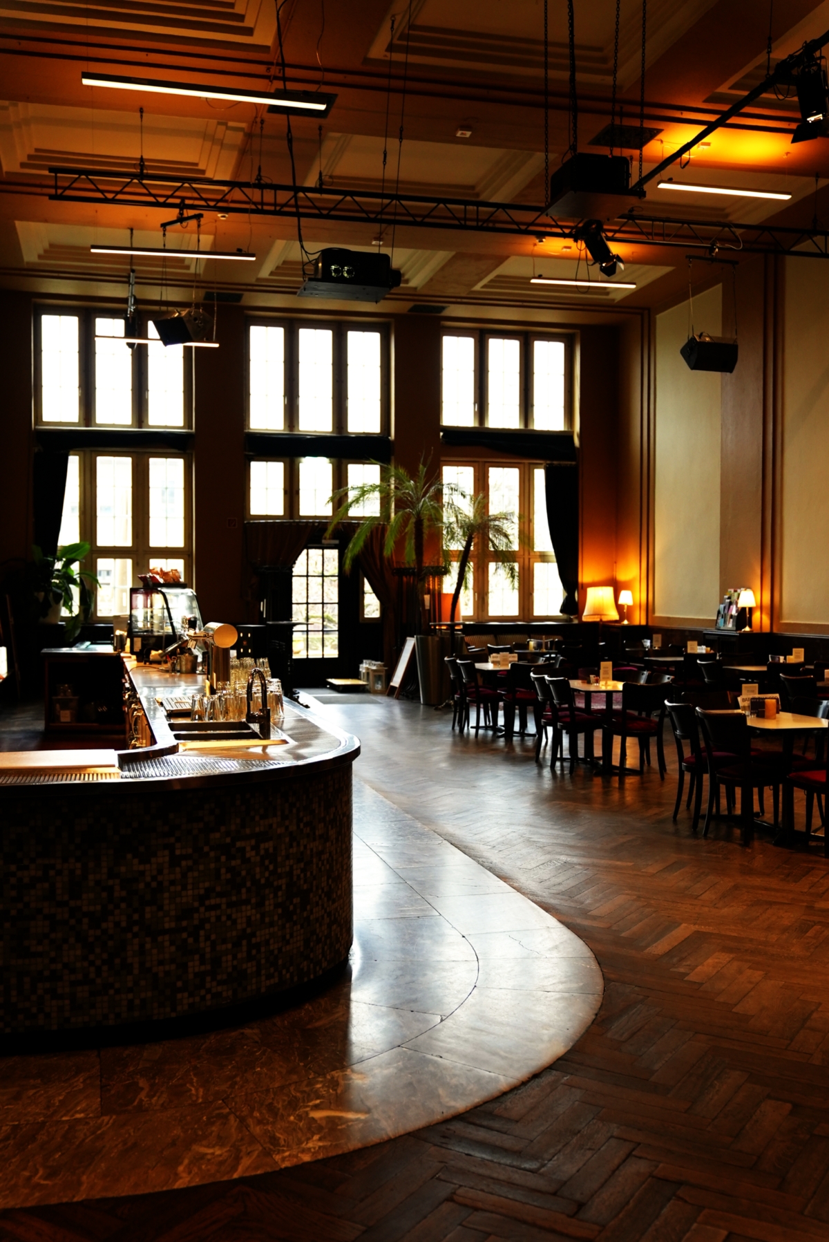 warmer Innenraum, Bar links und rechts Stühle und Tische mit Parkettboden